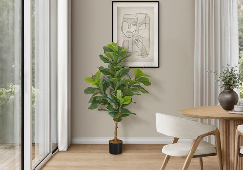 A tall artificial fiddle leaf fig tree with large green leaves stands in a modern dining room next to a wooden table.
