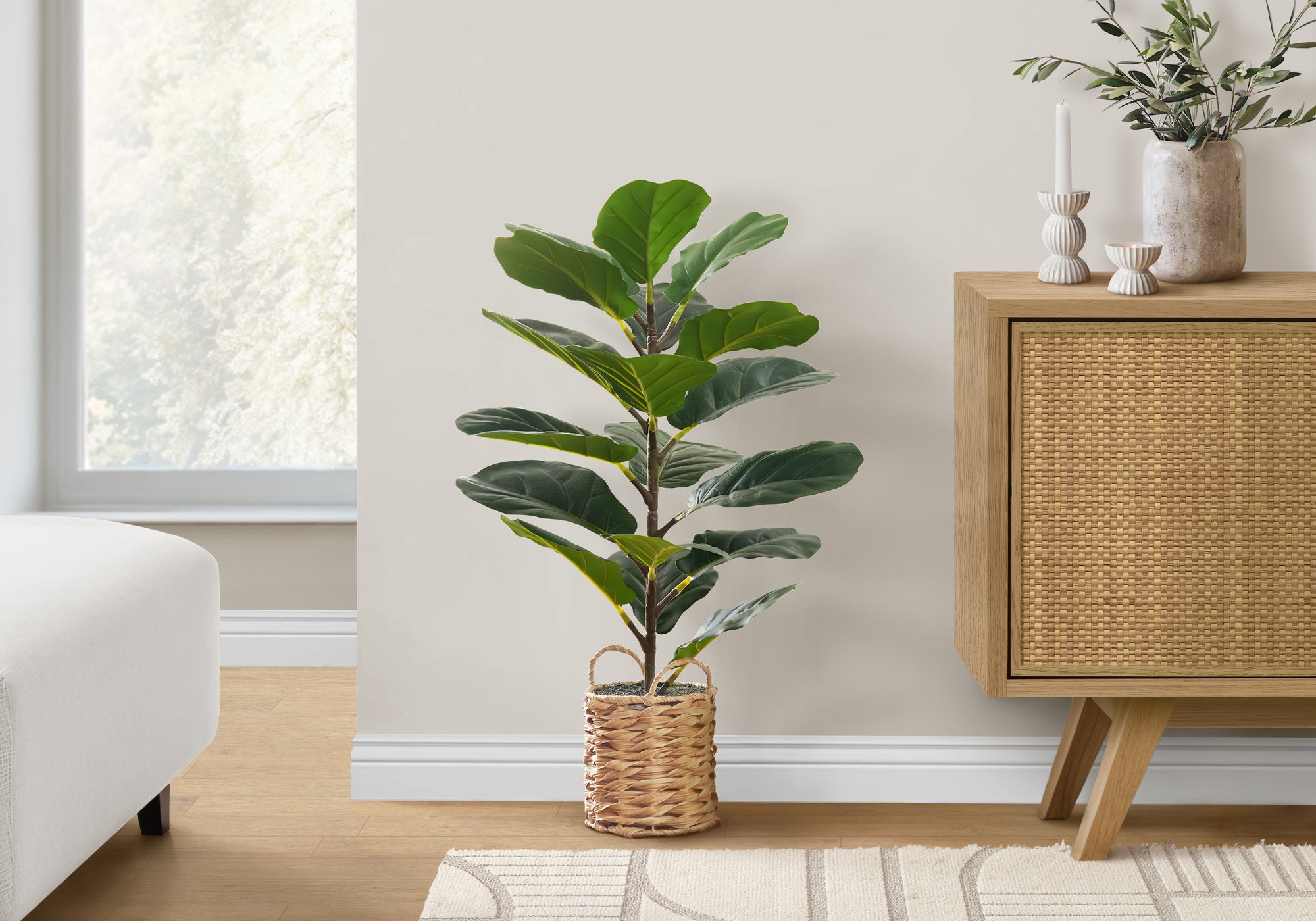 An artificial fiddle leaf fig bush in a woven boho basket styled in a bright, neutral living room.