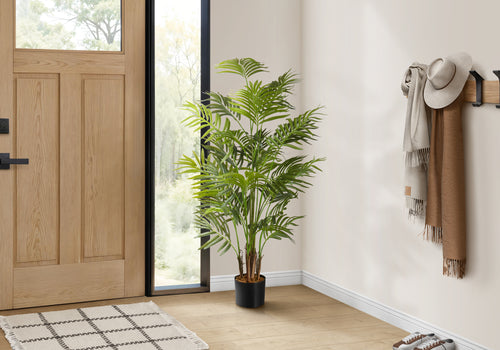 Large faux Areca Palm Tree styled in a bright entryway beside a wood front door