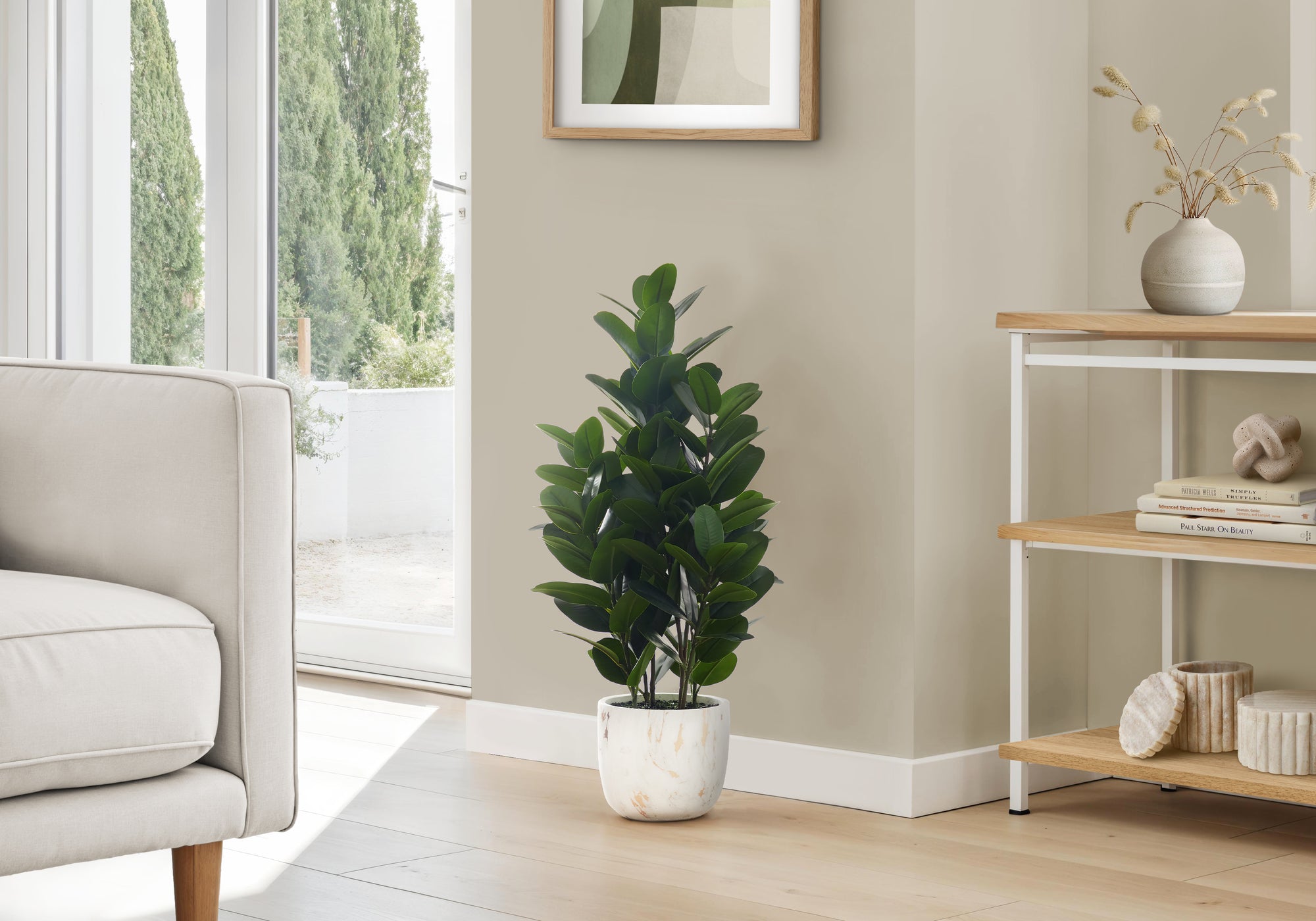 A medium-sized artificial Garcinia bush with dense, dark green leaves in a white marbled pot, placed in a living room.