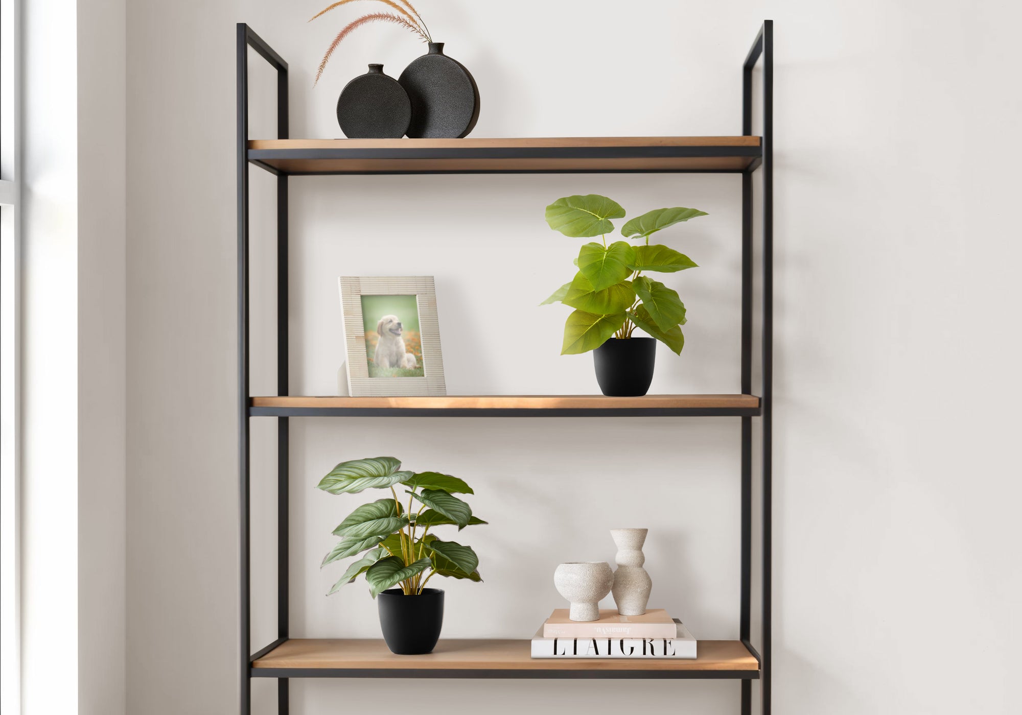 Two small artificial potted plants displayed on a modern metal and wood shelving unit with decor items.