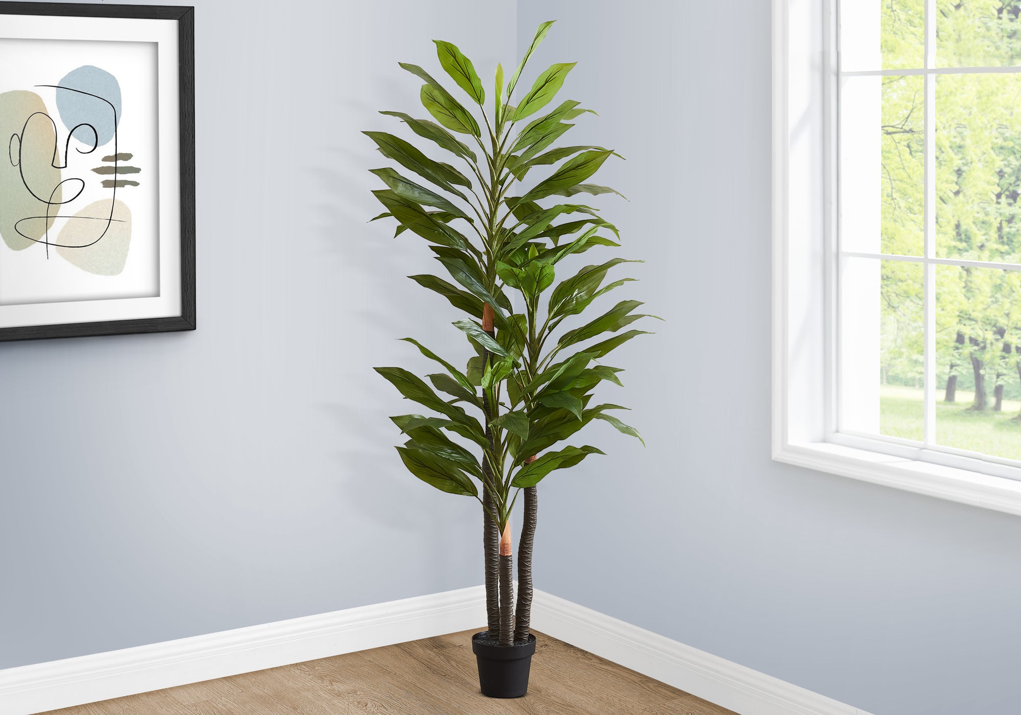 A tall artificial Dracaena tree with layered trunks and long green leaves standing in the corner of a room.