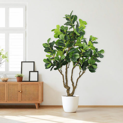 A tall artificial fiddle leaf fig tree in a white pot standing next to a wooden sideboard with cane detailing.