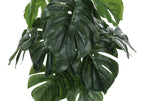 Close-up of the large, split green leaves of an artificial Monstera plant against a white background.