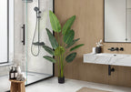 Large faux Bird of Paradise plant styled in a modern bathroom corner beside a shower