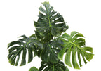 Close-up of the large, split green leaves of an artificial Monstera plant against a white background.