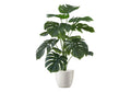 A medium-sized artificial Monstera plant with large, split green leaves in a simple white pot against a white background.