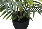 Close-up of an artificial areca palm plant showing green fronds and stems in a simple black pot.