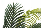 Close-up of dark and light green artificial palm fronds with feathered leaves against a white background.
