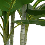 Close-up of the textured, light-colored stalks and broad green leaves of an artificial Dieffenbachia plant.