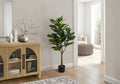 A large artificial fiddle leaf fig tree in a black pot standing next to a light wood cabinet in a bright living room.