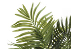 Close-up of feathery green fronds on a faux Areca palm tree against a white background.