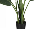 Close-up of the black nursery pot and green stems on a faux Bird of Paradise plant