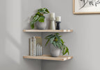 Two artificial potted plants displayed on light wood corner shelves alongside candles and books.